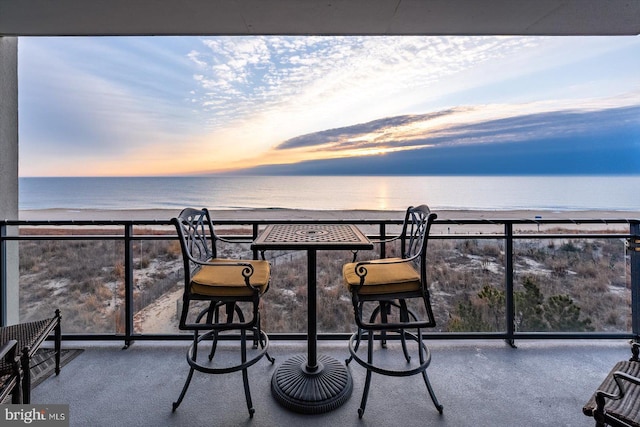 balcony at dusk with a water view and a beach view