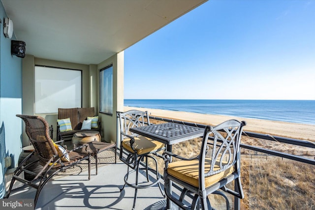 balcony featuring a view of the beach and a water view