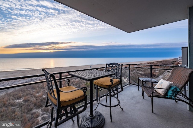 balcony at dusk featuring a water view