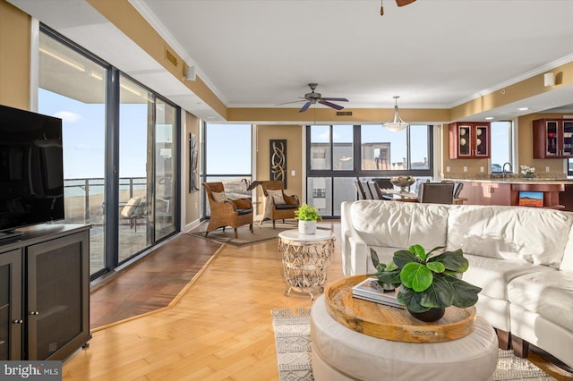 living room featuring ornamental molding, sink, ceiling fan, and light hardwood / wood-style floors