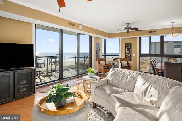 living room with ornamental molding, ceiling fan, and light wood-type flooring