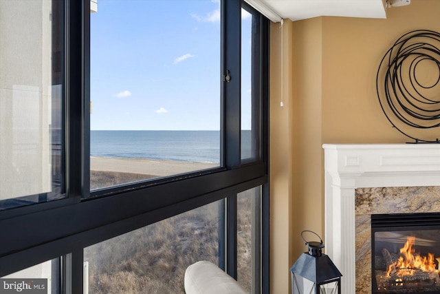 interior details with a view of the beach, a high end fireplace, and a water view