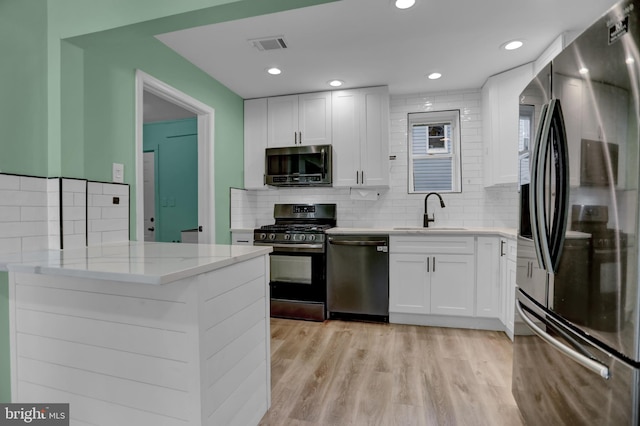 kitchen featuring kitchen peninsula, sink, white cabinetry, and stainless steel appliances