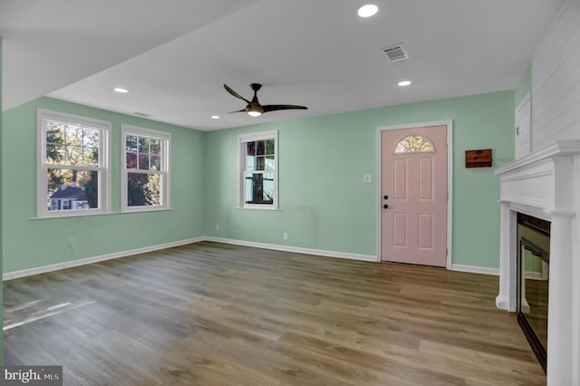 unfurnished living room with light wood-type flooring, a large fireplace, and ceiling fan