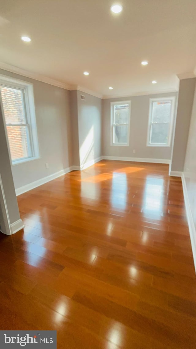 empty room with crown molding and hardwood / wood-style floors