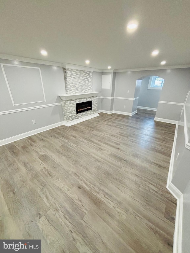 unfurnished living room with wood-type flooring and a stone fireplace