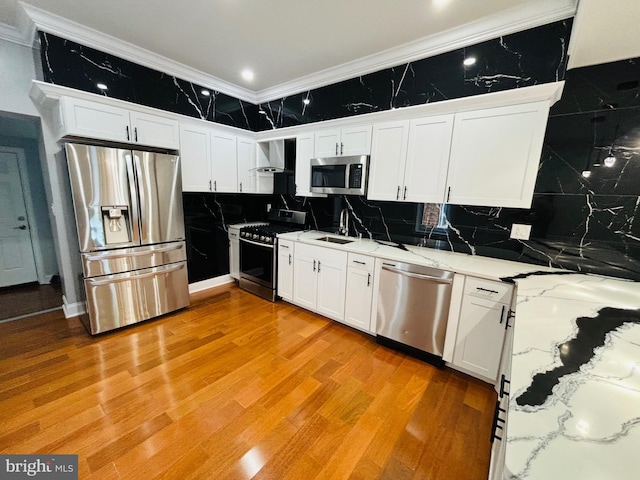 kitchen with appliances with stainless steel finishes, light hardwood / wood-style floors, ornamental molding, decorative backsplash, and white cabinets