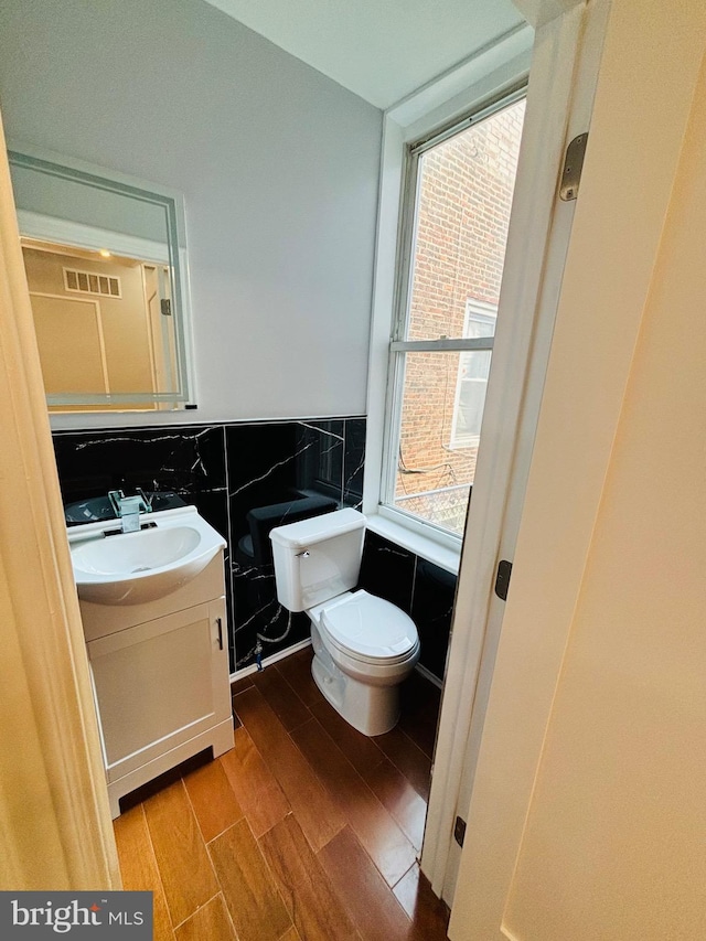 bathroom with hardwood / wood-style floors, toilet, tile walls, decorative backsplash, and vanity