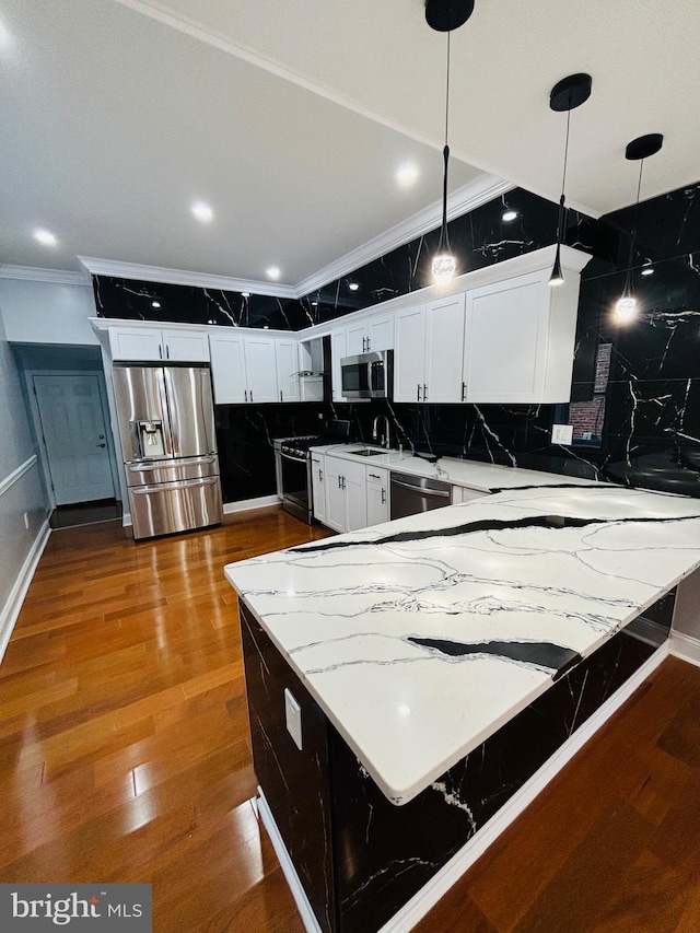 kitchen with crown molding, backsplash, decorative light fixtures, wood-type flooring, and appliances with stainless steel finishes