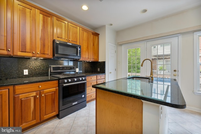 kitchen with brown cabinets, a sink, black gas range oven, and light tile patterned floors