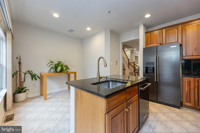 kitchen featuring light tile patterned floors, a sink, visible vents, dark stone countertops, and stainless steel fridge