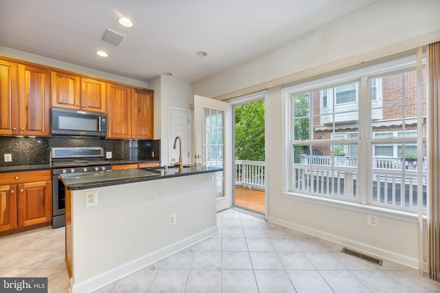 kitchen with visible vents, stainless steel range with gas cooktop, black microwave, and backsplash