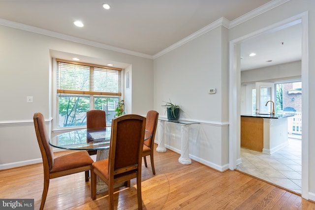 dining room with light wood-type flooring, crown molding, baseboards, and recessed lighting