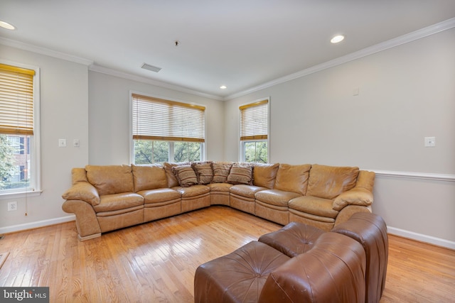 living room with ornamental molding, light wood-type flooring, visible vents, and baseboards