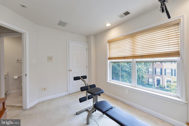 exercise area featuring baseboards, visible vents, and light colored carpet