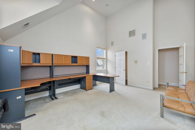 office area featuring high vaulted ceiling, visible vents, and light carpet