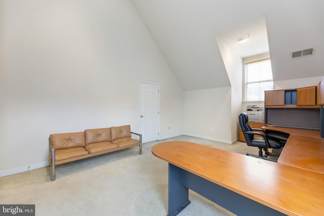 office space with vaulted ceiling, baseboards, visible vents, and light colored carpet