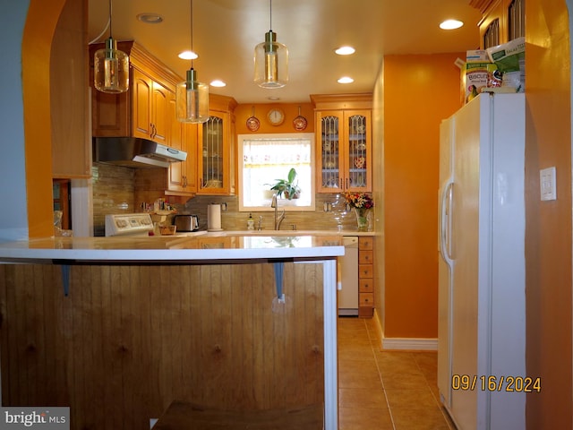 kitchen featuring white appliances, backsplash, a kitchen breakfast bar, hanging light fixtures, and kitchen peninsula