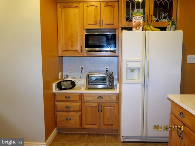 kitchen featuring white refrigerator with ice dispenser, light tile patterned floors, and stainless steel microwave