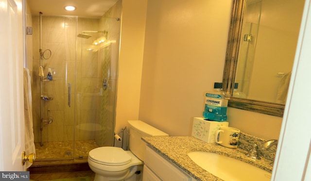 bathroom featuring vanity, toilet, and a shower with shower door