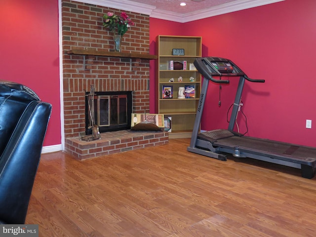 exercise area featuring hardwood / wood-style flooring, crown molding, and a brick fireplace