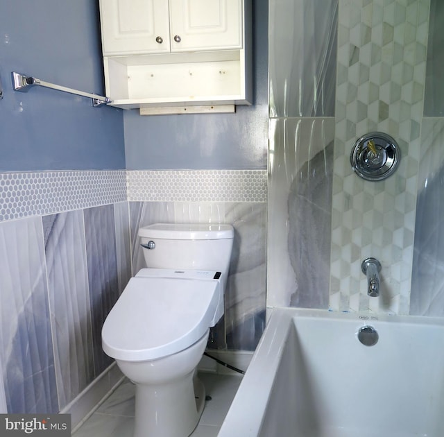 bathroom featuring tile patterned floors, tiled shower / bath, tile walls, and toilet