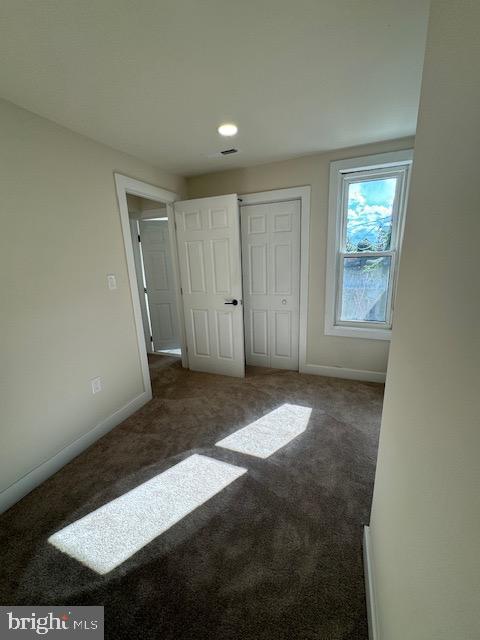 unfurnished bedroom featuring a closet, baseboards, and carpet flooring