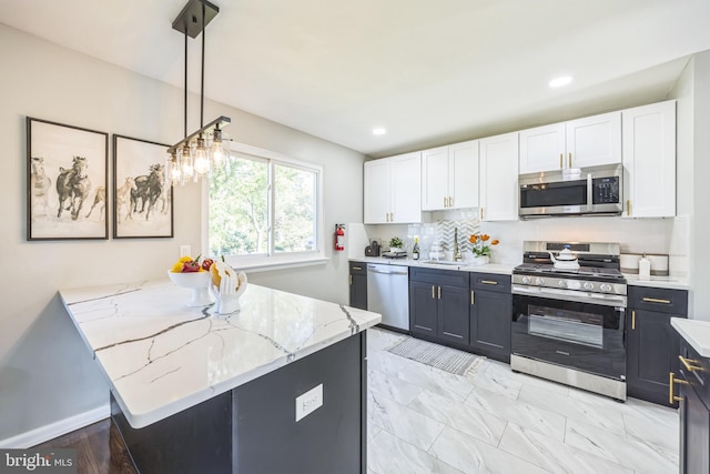 kitchen featuring white cabinets, hanging light fixtures, appliances with stainless steel finishes, kitchen peninsula, and tasteful backsplash