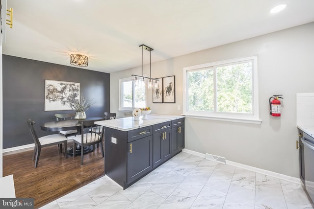 kitchen featuring hanging light fixtures, kitchen peninsula, an inviting chandelier, and light stone countertops