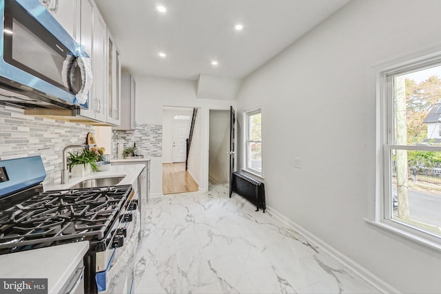 kitchen featuring sink, appliances with stainless steel finishes, radiator heating unit, and plenty of natural light