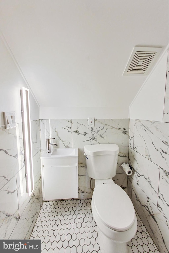 bathroom with tile walls, vanity, toilet, and tile patterned flooring