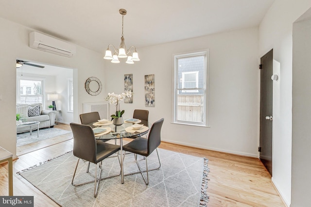 dining area with wood-type flooring, a wall mounted air conditioner, and ceiling fan with notable chandelier