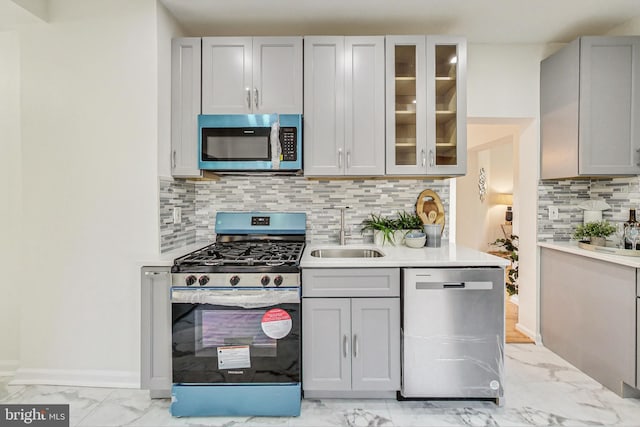 kitchen featuring gray cabinets, sink, stainless steel appliances, and tasteful backsplash