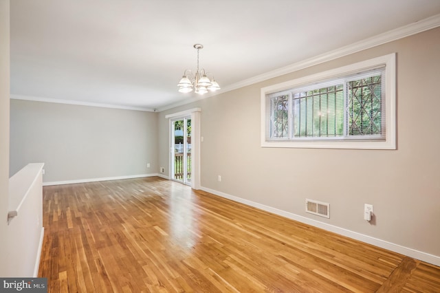 empty room with crown molding, plenty of natural light, light hardwood / wood-style flooring, and a chandelier