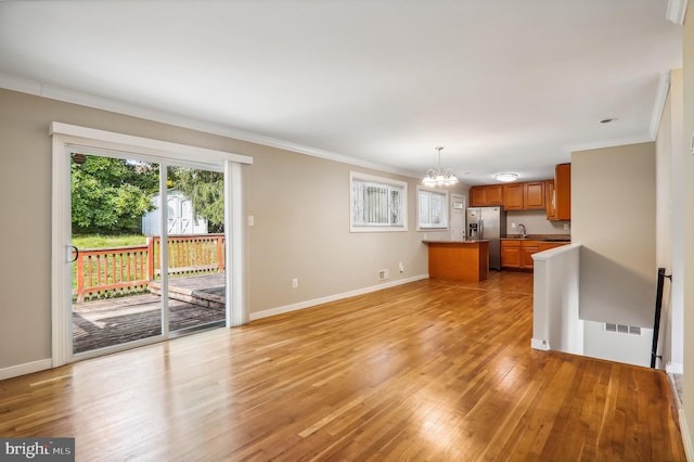 unfurnished living room featuring ornamental molding, light hardwood / wood-style flooring, and a chandelier