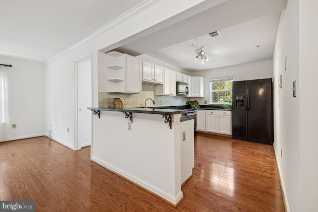 kitchen with black appliances, backsplash, wood-type flooring, kitchen peninsula, and white cabinets