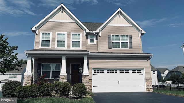 craftsman inspired home with stone siding, covered porch, driveway, and an attached garage