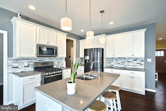 kitchen with dark hardwood / wood-style floors, a kitchen island with sink, stainless steel appliances, sink, and white cabinetry