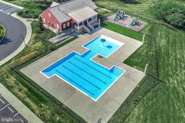 view of pool featuring a playground, a yard, and a patio area