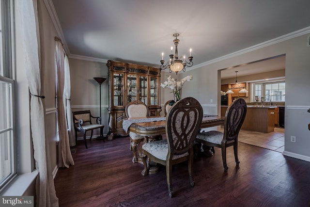 dining area with crown molding, dark wood-type flooring, and an inviting chandelier