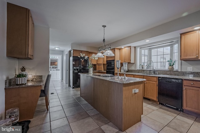 kitchen featuring hanging light fixtures, light tile patterned floors, sink, black appliances, and a center island