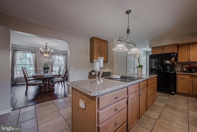 kitchen featuring pendant lighting, a kitchen island, light hardwood / wood-style flooring, stovetop, and black refrigerator with ice dispenser