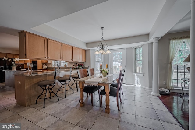 tiled dining area featuring a chandelier and decorative columns