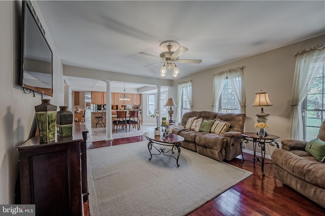 living room featuring ornate columns, plenty of natural light, dark hardwood / wood-style floors, and ceiling fan with notable chandelier