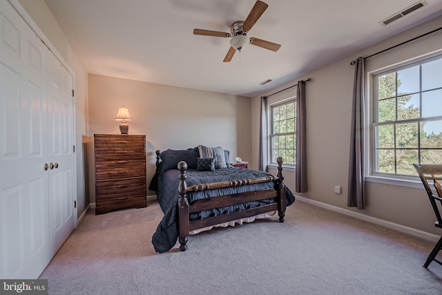 carpeted bedroom with a closet, multiple windows, and ceiling fan