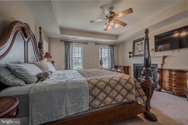 bedroom featuring ceiling fan, a raised ceiling, and carpet flooring