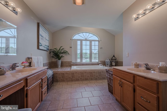 bathroom featuring tile patterned floors, vanity, and tiled bath