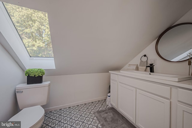 bathroom featuring lofted ceiling with skylight, toilet, and vanity