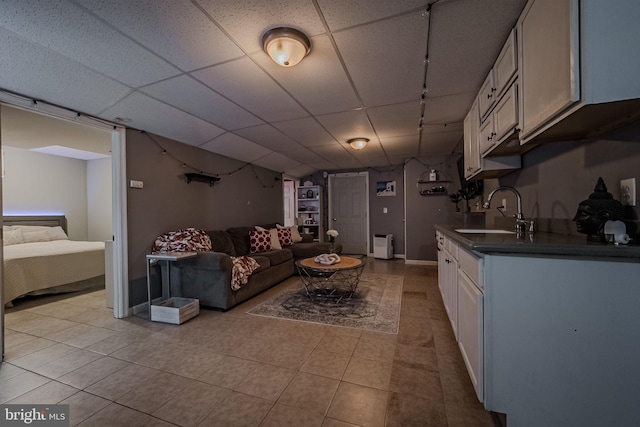 living room featuring a paneled ceiling, sink, and light tile patterned floors