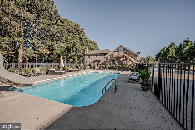 view of swimming pool featuring a water slide and a patio